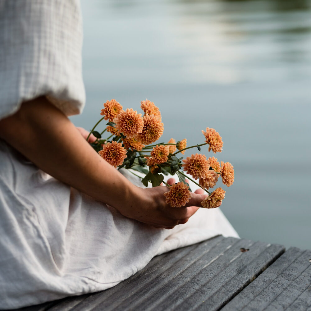 Woman siting on a dock with holding flowers